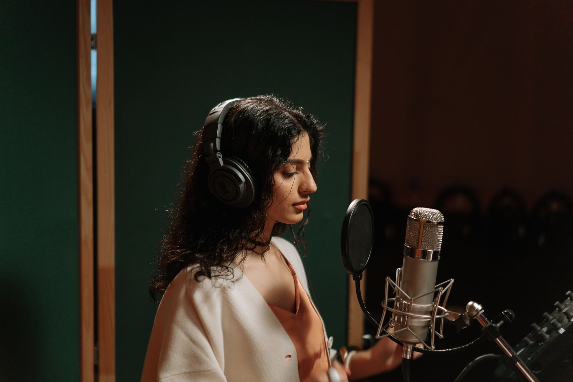 A female singer recording vocals in a professional music studio with a microphone